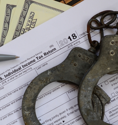 Police handcuffs lie on the tax form 1040. The concept of problems with the law in the aftermath of non-payment of taxes