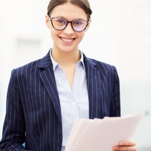 Waist up portrait of smiling young businesswoman wearing glasses smiling at camera, copy space
